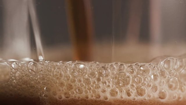 Macro dark beer pouring into a glass