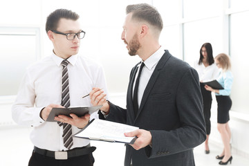 two employees discussing business documents in the office lobby.