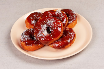 sweet donuts in caramel glaze in a pink plate on a gray background close-up