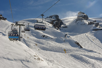People skiing and going up the mountain by chairlift at Engelberg on the Swiss alps