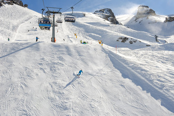 People skiing and going up the mountain by chairlift at Engelberg on the Swiss alps