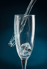 splash in a champagne glass against falling water on a dark blue background