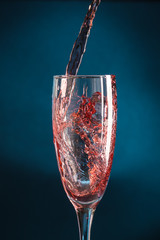 splash in a champagne glass from falling red wine on a dark blue background