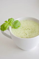 Healthy green tea matcha latte with soy and oat milk in a white tea cup decorated with basil and foam on top - a warm beverage to boost brain function and as a cancer prevention!