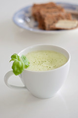 Healthy green tea matcha latte with soy / oat milk decorated with basil and foam on top - a warm beverage to boost brain function and as a cancer prevention! Crisp bread and butter blurry background