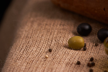 olive is on the table in background of bread, baguette and cheese. Selective focus