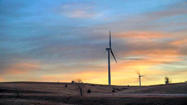 Time lapse wind turbines against a background of burning sky