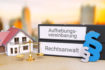 Aufhebung Mietvertrag. Ordner beschriftet mit den Wörtern Aufhebungsvereinbarung und Rechtsanwalt liegen neben einem Haus, einer Waage sowie Paragrafen-Zeichen auf einem Schreibtisch. 