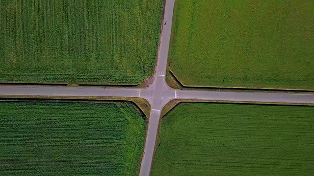 Spiral drone view of a crossroad with 1 car passing