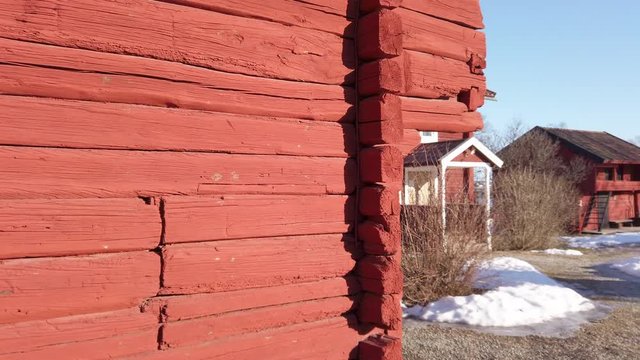 Panning shot of some falu red old buildings filmed on a beautiful sunny winter day near Dalarna in Sweden. Camera movements from left to right revealing more buildings. Filmed in slow motion at 4K.