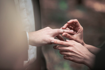 closeup of the groom places the ring on the bride's finger.