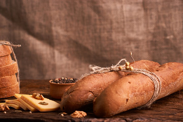 Peppercorns in a wooden bowl on table with cheese and two baguettes. Homemade food