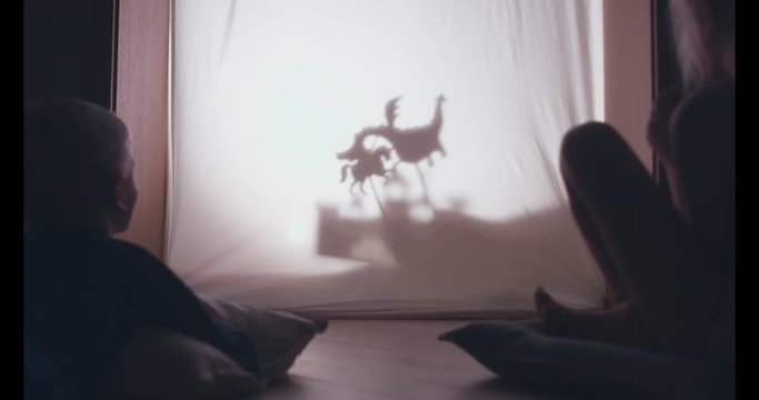 Cute little siblings brother and sister watching a kingdom tale in the shadow theatre at home. 4K UHD 60 FPS SLOW MOTION