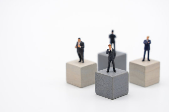 Miniature 4 people businessmen standing on Wooden cube Investment Analysis Or investment Blockchain concept. as background business concept and strategy concept with copy space.