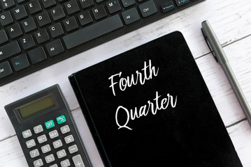 Top view of calculator,keyboard,pen and notebook written with Fourth Quarter.