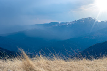 Early spring in the mountains, with peaks still covered with snow. Panoramic view of a natural alpine landscape in a sunny day, with majestic Bucegi mountains in the Carpathians.