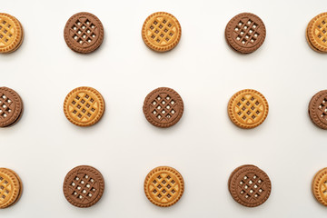 Vanilla and chocolate cookies on a white background, chocolate one in the center. View from above