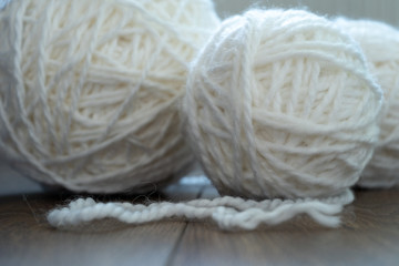 Close-up. Three spherical skeins of white wool on a wooden surface