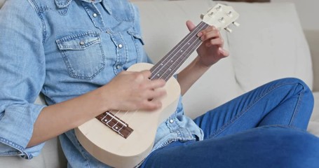 Woman play with ukulele at home