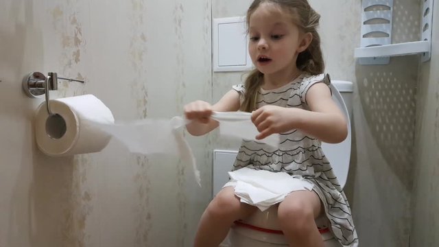 the little girl pulls the toilet paper