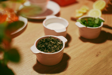 Green tea, sugar and mint in bowls on a wooden table. Pickled tea, Herbal Tea Leaf