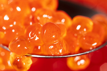 Red caviar on the spoon as a background