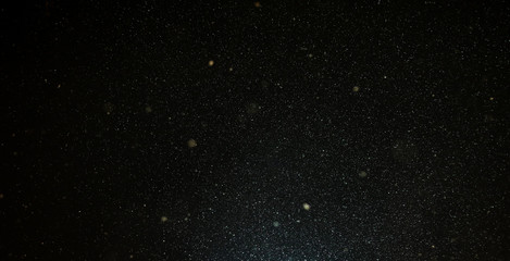 Snow flies in the sky at night as a background