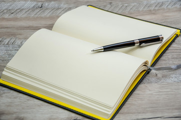 notebook and pen on wooden background