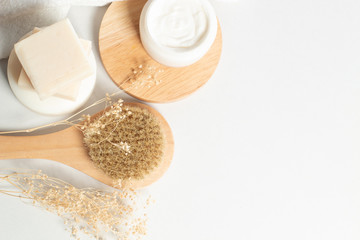 herbal with soap and bottle with facial cream with wood dish and dried flower and bath brush in top view