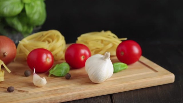 pasta ingredients on wooden table panning shot .fettuccine cherry tomatoes garlic mushrooms basil