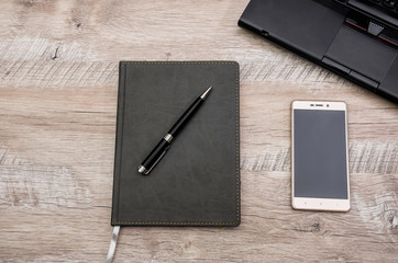 notebook, pen, smartphone and laptop on a wooden background