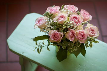 bouquet of roses on a mint-green wooden bench