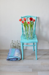 vintage turquoise chair with pink tulips in glass vases and a folded quilt