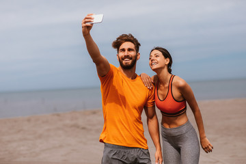 Young sports couple taking selfie on the beach