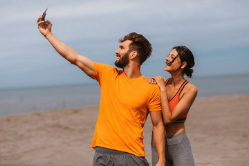Young sports couple taking selfie on the beach