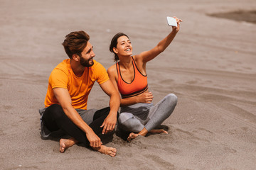 Young sports couple taking selfie on the beach