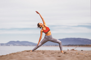Young woman practicing yoga on the beach