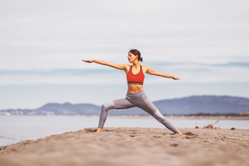 Young woman practicing yoga on the beach