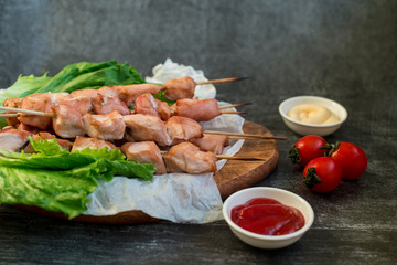 Chicken breast skewers cooked in homemade oven with red and white sauce and tomatoes.