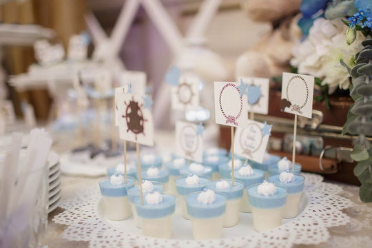 blue and white christening candy bar: close up photo of pana cotta with sticks with messages