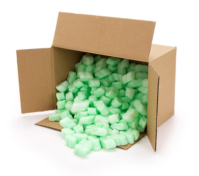 Brown open corrugated cardboard moving box, filled with green styrofoam pellets or packing peanuts falling out on white background. Contains clipping path.