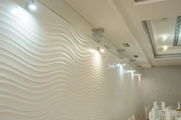 White wave texture wall and a white ceiling both decorated with lights and ornaments in a banquet hall