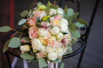 close up photo of a bridal bouquet from white and pink roses and eustoma on a iron chair