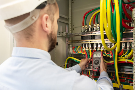 Electrician working with multimeter in electrical cabinet
