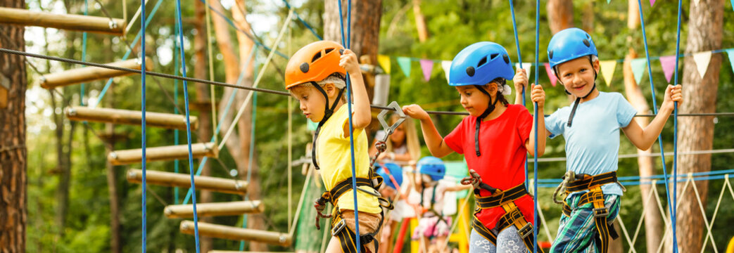 Children - a boy and a girl in the rope park pass obstacles. Brother and sister climb the rope road