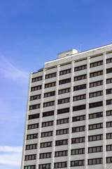 Fototapeta premium Vertical corner bottom shoot of modern reinforced concrete building with blue air
