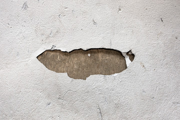 A cracked white wall with a hole
