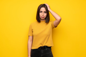 Young woman over yellow wall with an expression of frustration and not understanding