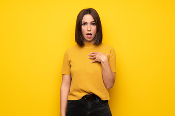 Young woman over yellow wall surprised and shocked while looking right