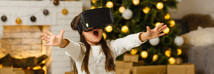 Portrait of little girl playing in virtual reality headset at home